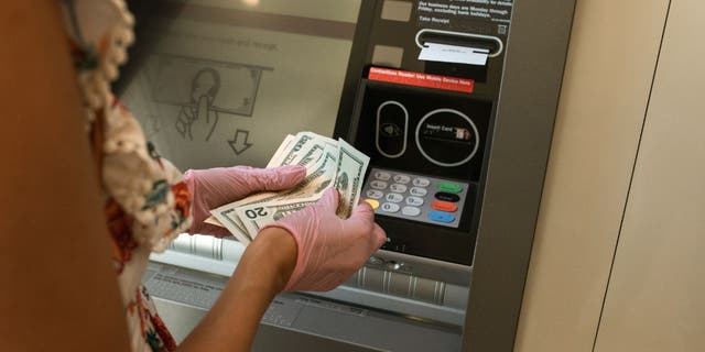 Mujer sosteniendo efectivo frente a un cajero automático