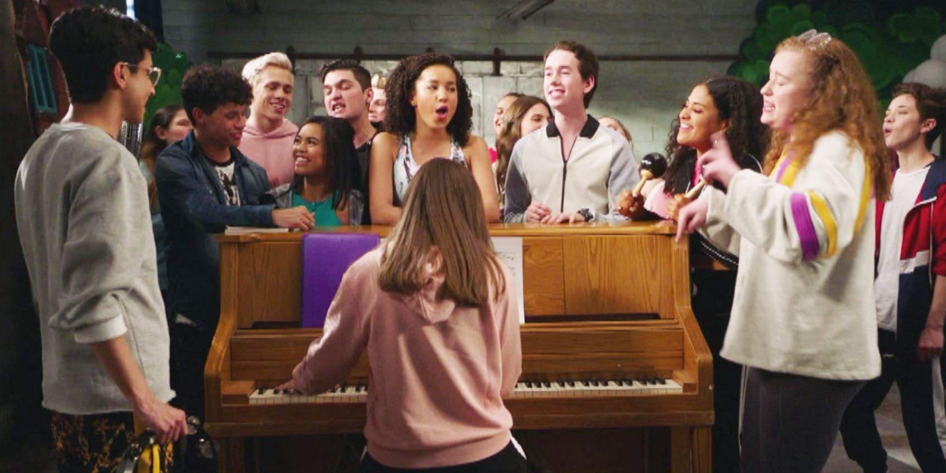 The cast of High School Musical: The Musical: The Series singing around a piano