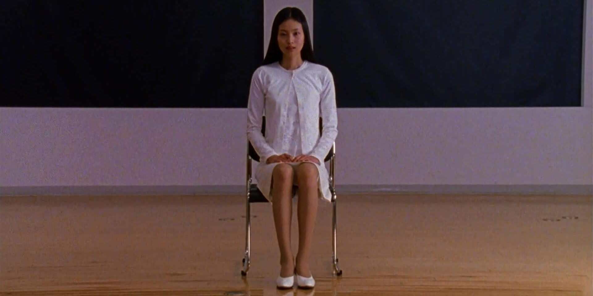 Asami sentada en una silla en Audition