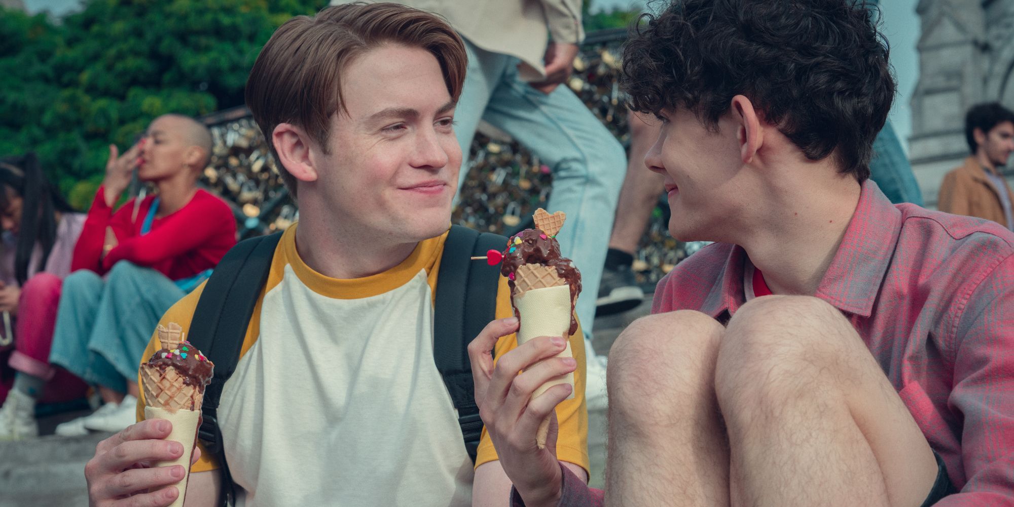 Kit Connor as Nick smiles at Joe Locke as Charlie as they eat ice cream in Heartstopper Season 2