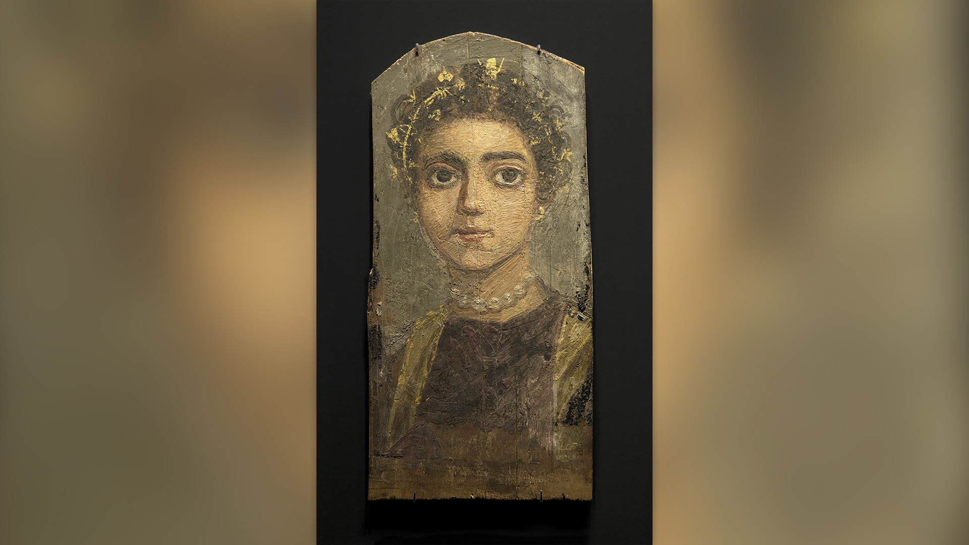 En este retrato, pintado sobre madera entre los años 120 y 130 d.C., vemos a una joven que lleva un collar de perlas y una corona de oro en el pelo.