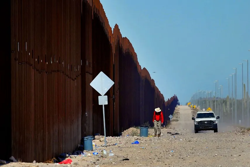El maestro de escuela jubilado Tom Wingo, del grupo Samaritanos Sin Fronteras, camina a lo largo del muro fronterizo mientras un agente de la Patrulla Fronteriza de EE. UU. patrulla el área, el martes 29 de agosto de 2023, cerca de Lukeville, Arizona. 