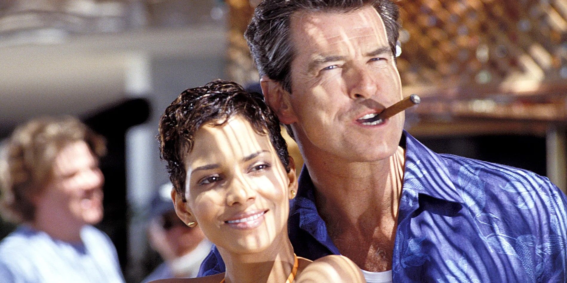 Muere otro día: Pierce Brosnan como James Bond fumando un cigarro y Halle Berry como Jinx parada bajo el sol. 