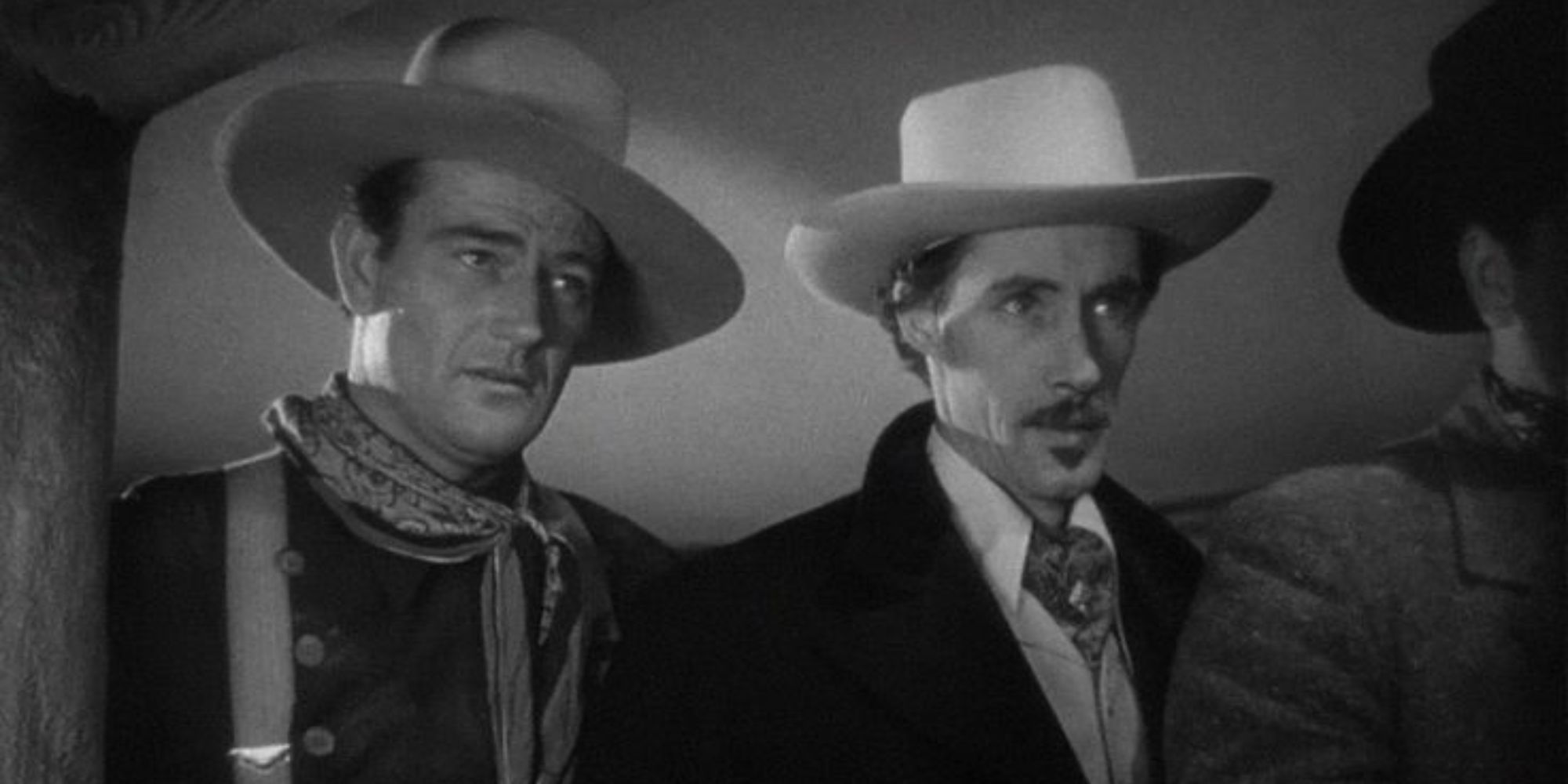 John Wayne y John Carradine parados uno al lado del otro mirando a alguien en Stagecoach