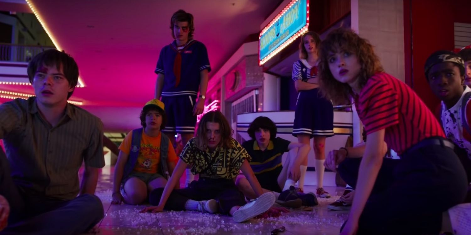 The teenagers all sitting and standing together in Starcourt in the Stranger Things Season 3 finale