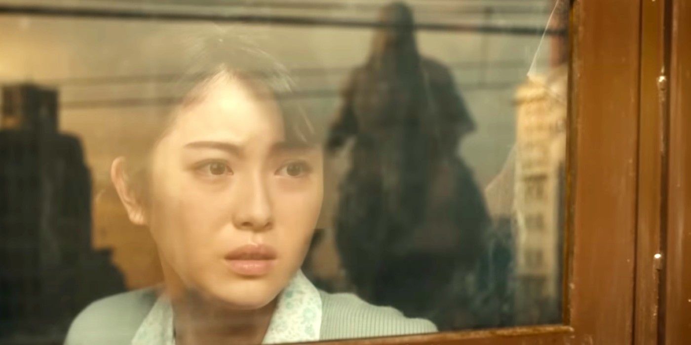 Una mujer mirando por una ventana a Godzilla en Godzilla Minus One