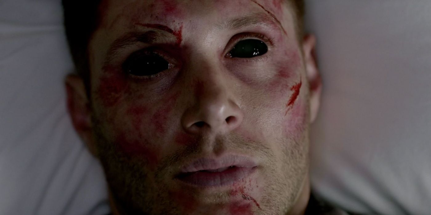 A cut and bloodied Dean Winchester awakens on a bed with pitch black demon eyes.