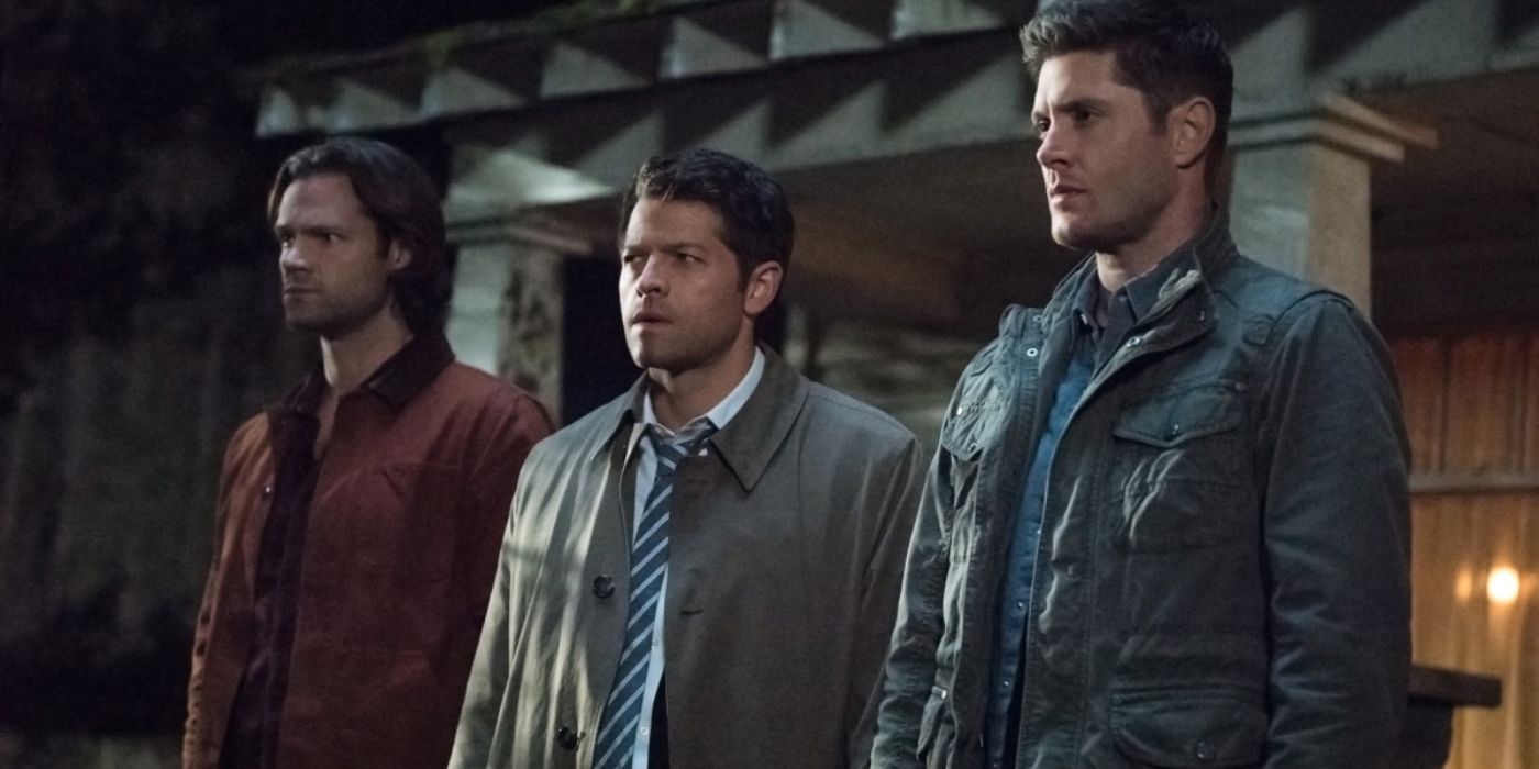 Sam Winchester, Castiel, and Dean Winchester stand shoulder-to-shoulder in front of a small house, waiting to face-off against Lucifer.