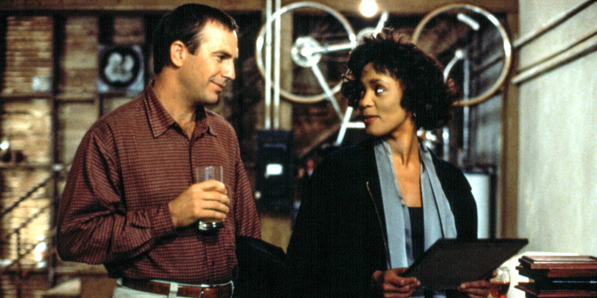 Whitney Houston and Kevin Costner as Rachel Marron and Frank Farmer, smiling at each other in The Bodyguard